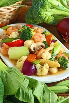 a white plate topped with vegetables next to broccoli and radishes on a wooden table