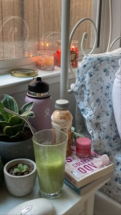 there is a cup and some plants on the window sill next to each other