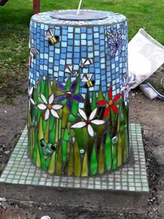 a mosaic style trash can sitting on top of a cement slab