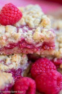 raspberry crumb bars stacked on top of each other with fresh raspberries