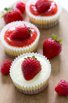 strawberry cupcakes with white frosting and fresh strawberries on the top, ready to be eaten