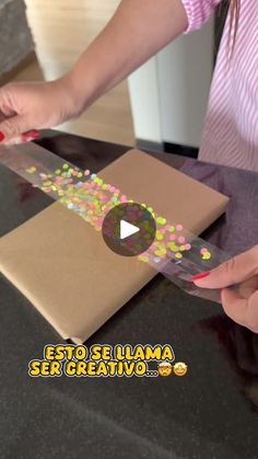 a woman is cutting into a brown box with confetti on it and the words esto se llama ser creativvo