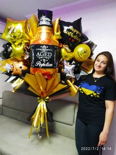 a woman standing next to a large bouquet of balloons and confetti in the shape of a bottle