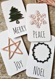 four christmas cards with words on them and some decorations hanging from the strings around them