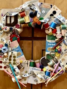 a wreath made out of old sewing threads and other crafting items sits on a door