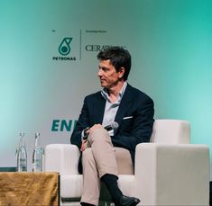 a man sitting in a chair talking to someone on the other side of the stage