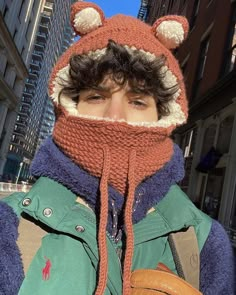 a young man wearing a knitted hat and scarf with an animal ear flap on his head