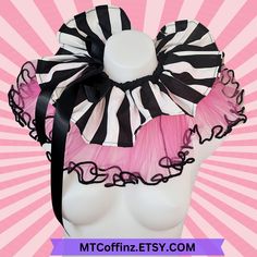 a white mannequin headpiece with black and pink ruffles on it