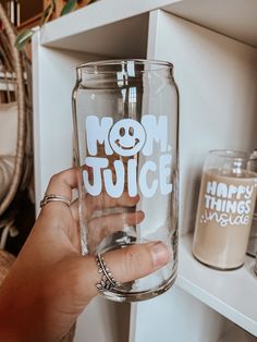 a person holding up a glass with the word mom juice on it