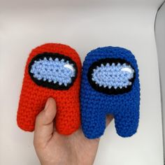 two crocheted mittens with eyes on each one being held by a person's hand