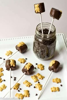 chocolate covered marshmallows and cookies in a mason jar on a white tray