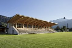 an empty stadium with grass and mountains in the background