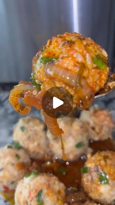 a spoon full of food with sauce being poured over it and on top of the meatballs