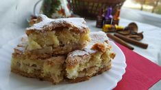 two pieces of cake sitting on top of a white plate next to a basket filled with cinnamon rolls