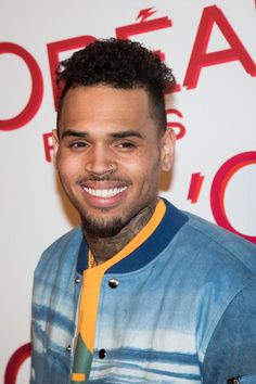 a man with a tie around his neck smiles at the camera while standing in front of a red and white wall