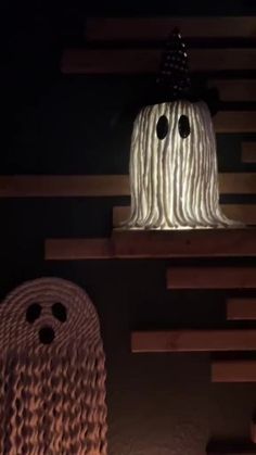 two halloween decorations on top of wooden shelves in a dark room with stairs and lights