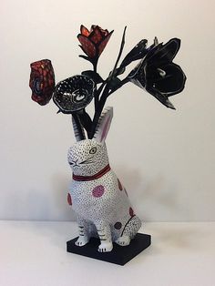 a white rabbit figurine with black flowers in it's head and legs