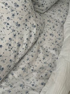 an unmade bed with blue flowers on it