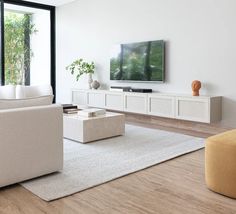 a modern living room with white furniture and large windows looking out onto the garden outside