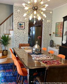 a dining room table with orange chairs and a chandelier hanging from the ceiling