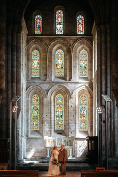 a bride and groom are standing in front of the stained glass windows at st mary's cathedral