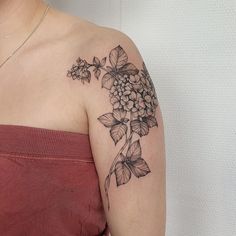 a woman's shoulder with flowers and leaves on her left arm, in black ink