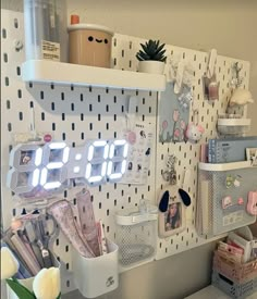 a white clock mounted to the side of a wall next to a shelf filled with office supplies