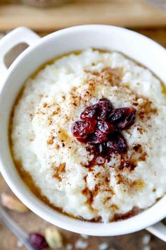 a white bowl filled with oatmeal and cranberries on top of a wooden table