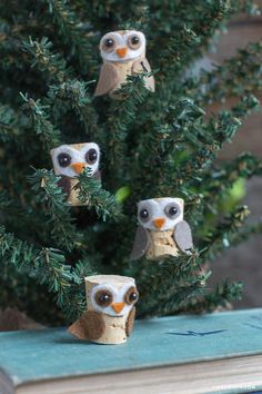 three little owls sitting on top of a book next to a small tree in the shape of an owl