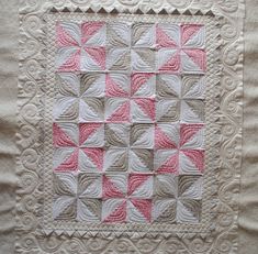 a pink and white quilted wall hanging