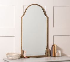 a mirror sitting on top of a dresser next to a vase and bookends