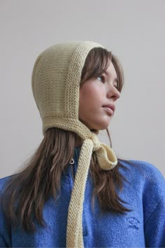 a woman wearing a knitted hat with a scarf around her neck and looking off into the distance