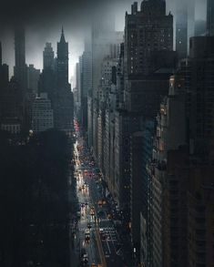 a city street filled with lots of tall buildings and traffic on a cloudy day at night