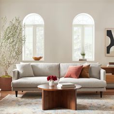 a living room with two windows and a couch in front of the window is a coffee table