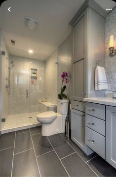 a white toilet sitting in a bathroom next to a walk - in shower and sink