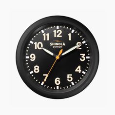 a black wall clock with yellow hands and numbers