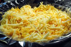 shredded cheese in a plastic container on top of a stove burner oven tray, ready to be cooked