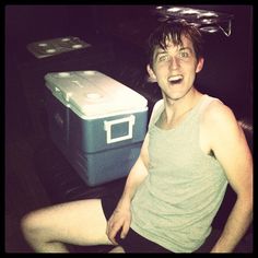 a young man sitting on the floor next to an ice chest and cooler in front of him