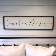 a bed with two pillows and a wooden sign above it