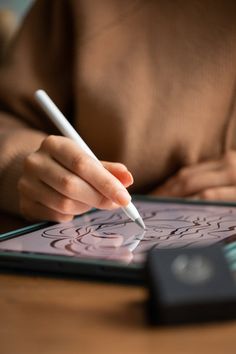 a person holding a pen and writing on a tablet