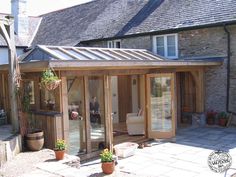 a small wooden building with glass doors on the front and side of it, sitting next to a patio