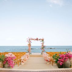 an outdoor ceremony set up on the beach with chairs and flowers in front of it