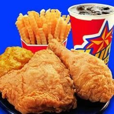 fried chicken and french fries are served on a plate with two cups of soda in the background