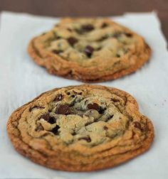 two chocolate chip cookies sitting on top of a white napkin