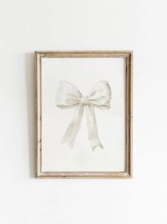 a white bow hanging on the wall above a framed painting in an old wooden frame