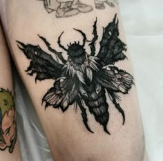 a close up of a person's legs with tattoos on them and an insect