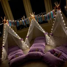 some pillows and lights are on the floor in front of two beds with purple covers