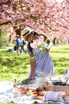 a woman standing next to a picnic basket with flowers