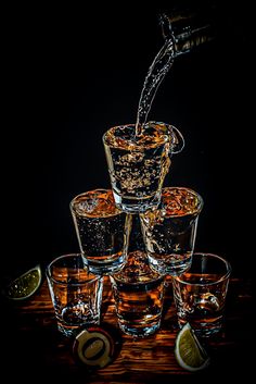 a pitcher pouring water into glasses filled with liquor