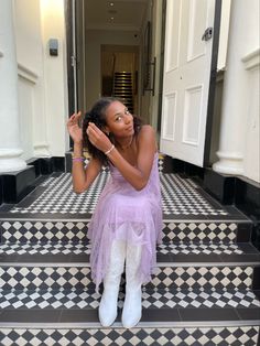 a woman sitting on the steps in front of a door with her hands up to her face